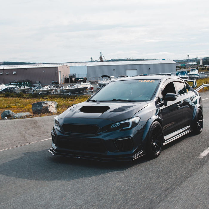 Expensive black tuned sports car with glossy surface and big front body kit riding on paved road out of city in daylight